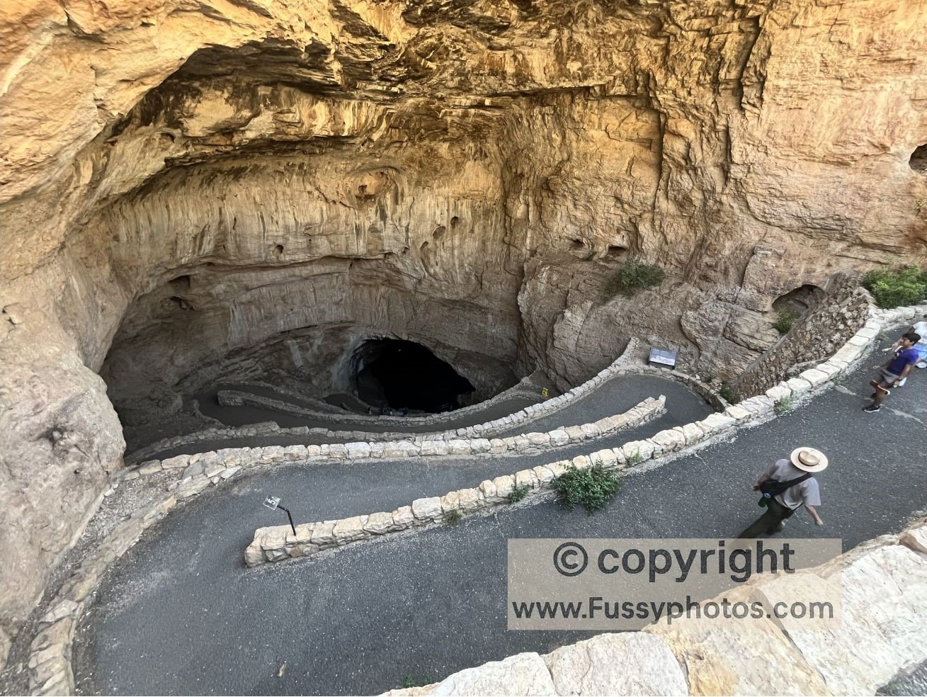 Visitors walking down the Natural Entrance at Carlsbad Caverns National Park, with the cave mouth darkening and the temperature dropping.