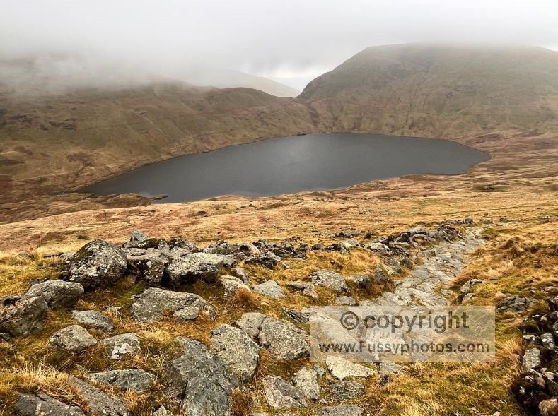 Climbing Toward Helvellyn: Paving‑Stone Ascent from the Coast to Coast Path (visible on the far side of the Tarn)