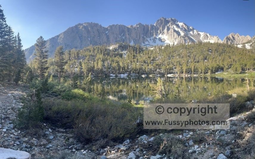 Morning light on Gilbert Lake, reflecting the surrounding ridgeline in calm, clear water.