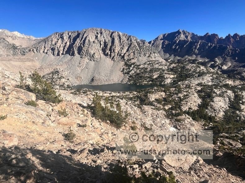 Looking down on Upper Lamarck Lake from the Lamarck Col Trail, with a clear high‑alpine view on the final‑day descent toward North Lake.