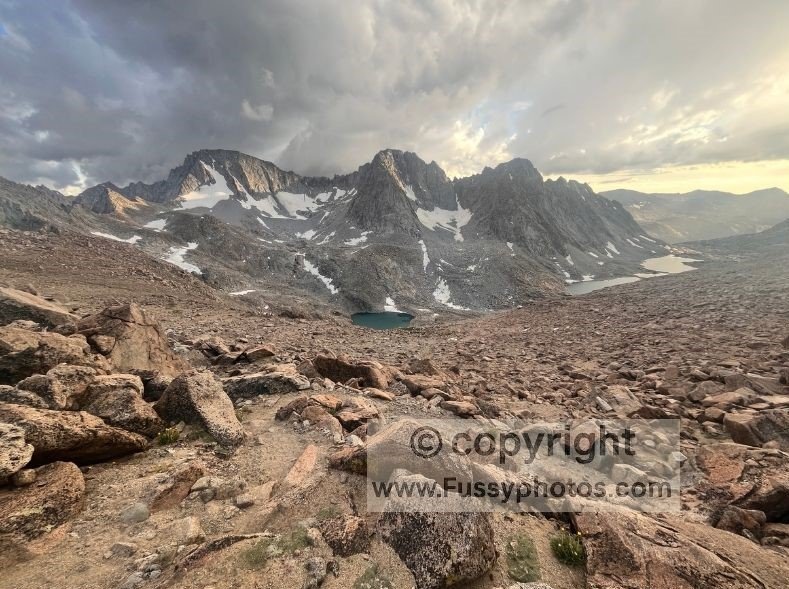 Looking west across Darwin Canyon as all its lakes come into view beneath brooding clouds and early sunset colours.