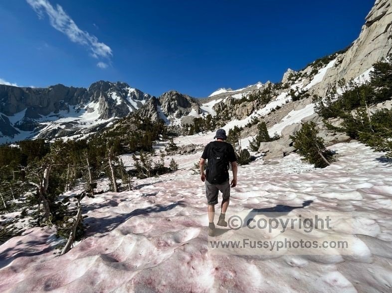 Crossing a patch of late‑season snow above Onion Valley, taking careful steps without crampons.