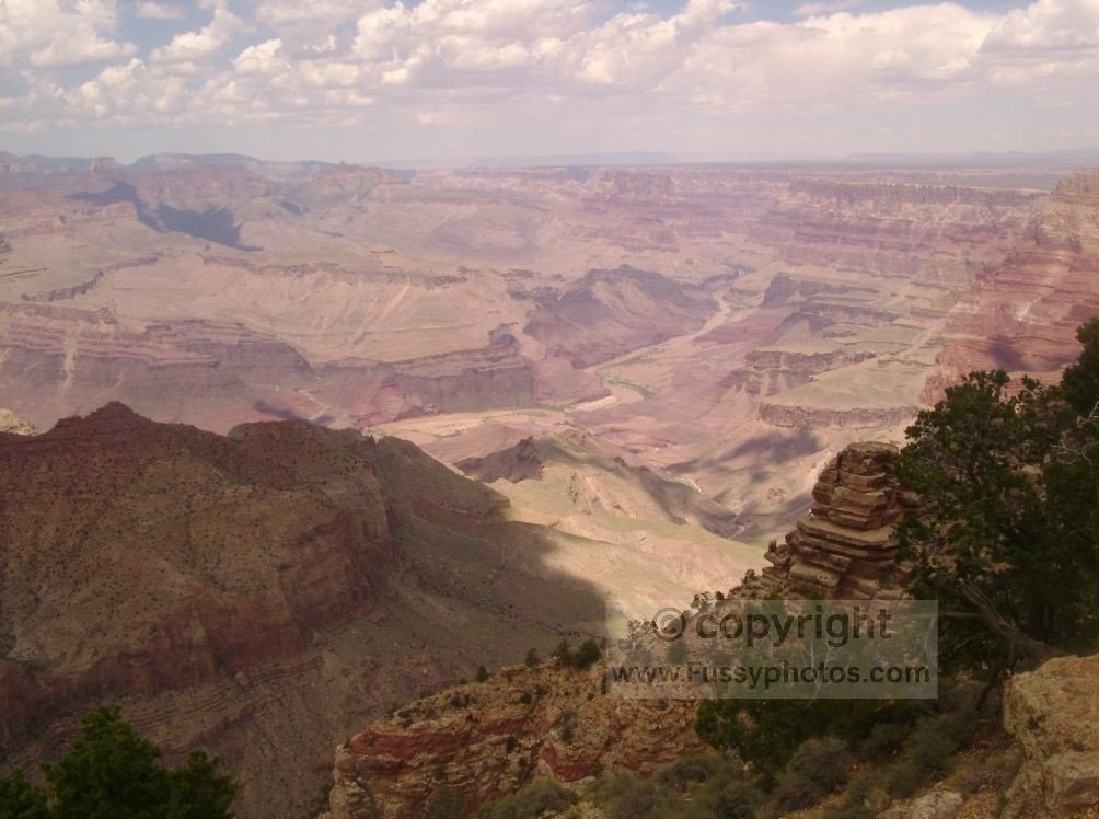 A wide view from the Rim Trail looking across the Grand Canyon, showing the broad cliffs and open landscape near the canyon edge.