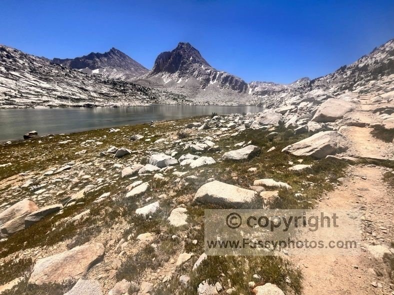 Southern view across Sapphire Lake, its deep blue water set in a remote high‑Sierra basin with rugged granite slopes surrounding it.