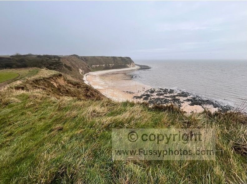 Sheltered sandy bay at Flamborough South Landing, with steps down from the cliffs and the lifeboat station behind the beach.