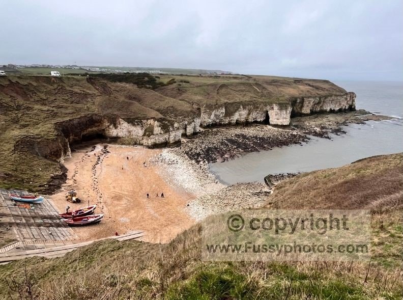Narrow bay at Flamborough, showing chalk cliffs and low‑tide rocks with no sea stacks in view.