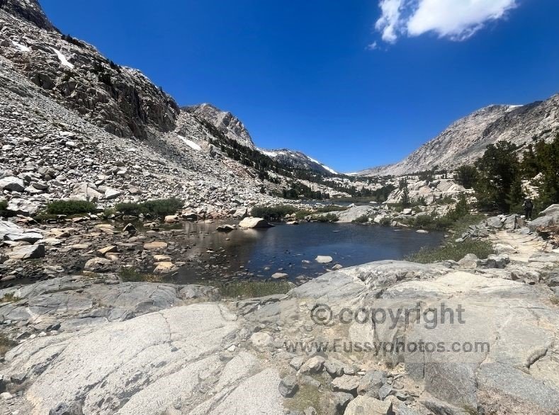 High‑alpine terrain along the Piute Pass Trail with gentle gradients, scattered granite slabs, and wide views toward the eastern Sierra crest.