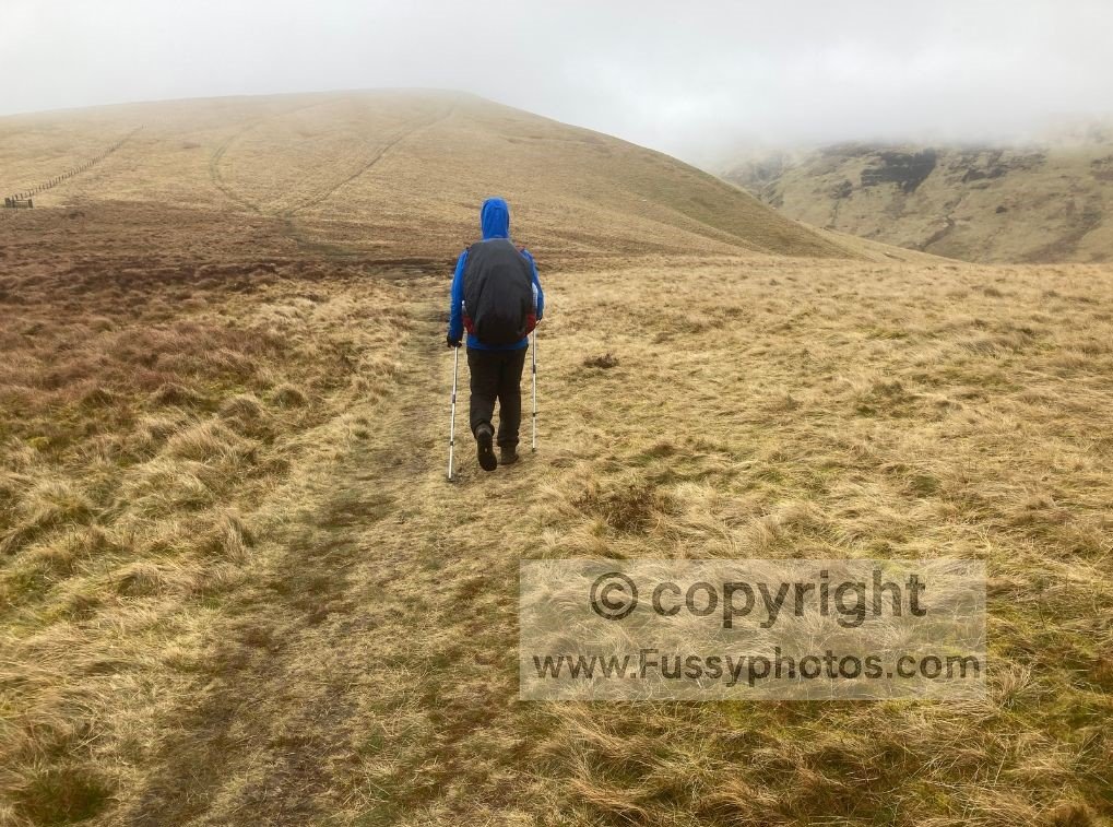 Walker ahead in poor weather on the Pennine Way, with rain and low cloud reducing visibility.