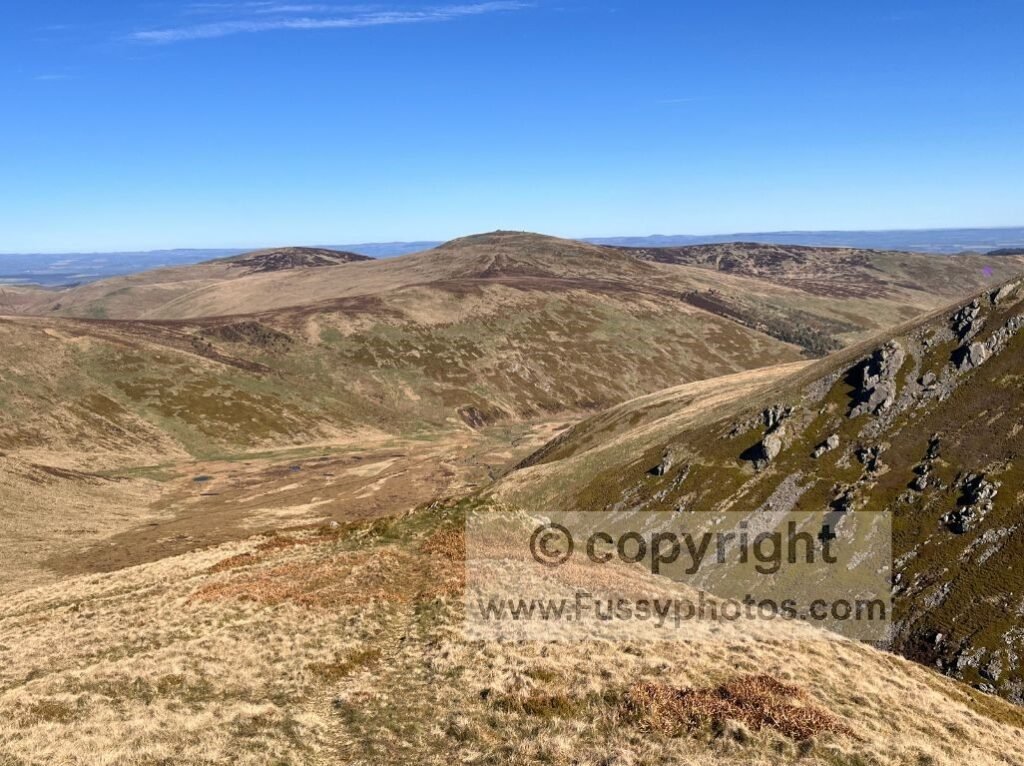 Southward view towards The Schill and College Valley from the descent of Auchope Cairn, showing remote hills and open moorland.