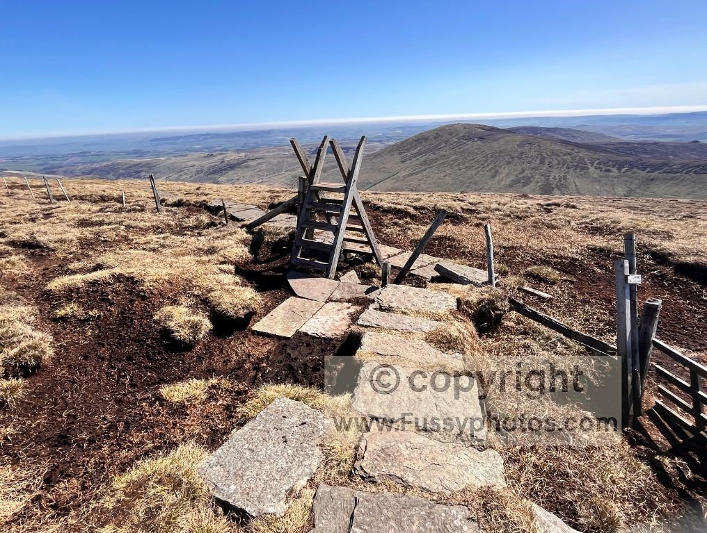 Wooden stile in the foreground where the descent from The Cheviot steepens towards Scald Hill.