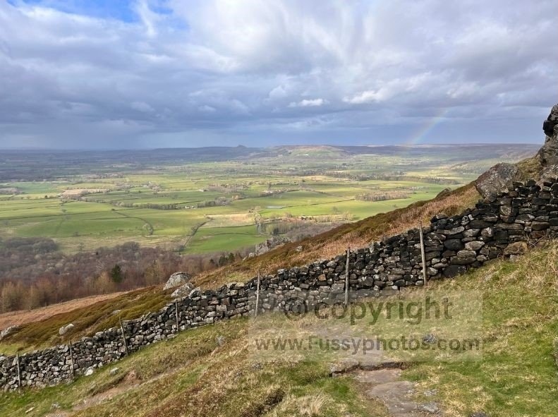 View into the Vale of Mowbray on the Coast to Coast, with a rainbow visible after rain as the path descends from the ridge.