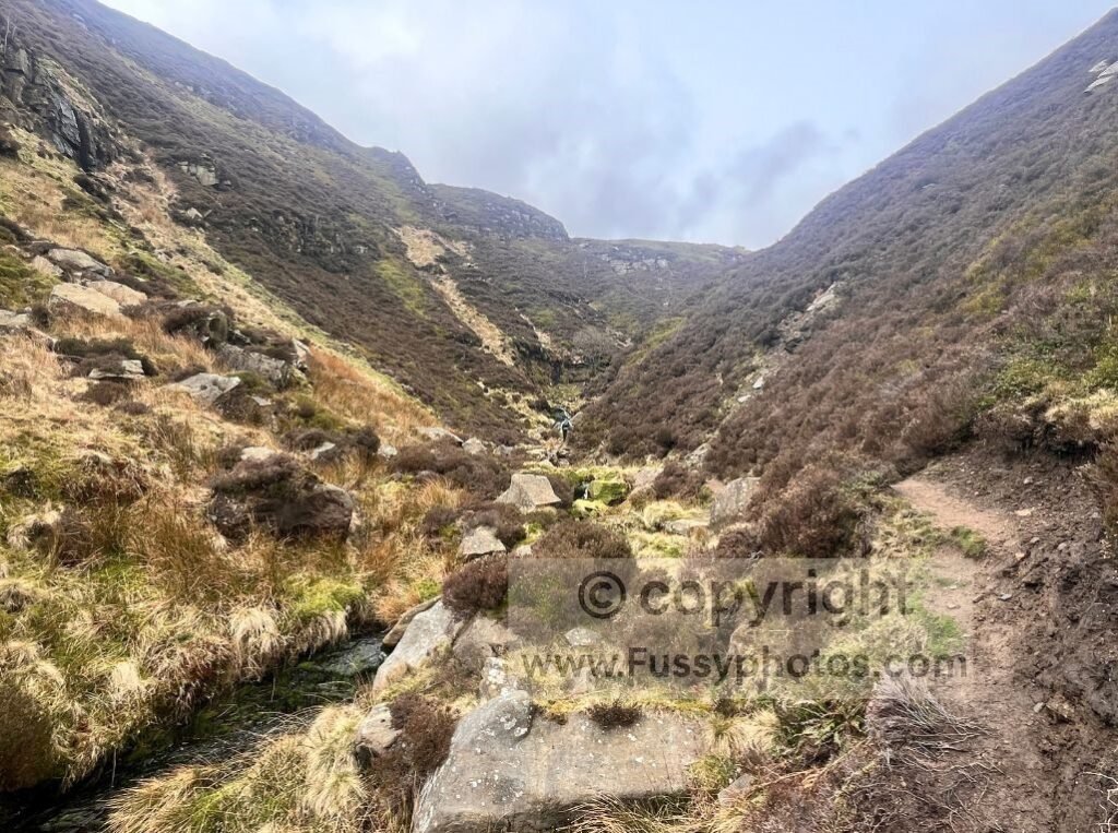 Steep V‑shaped valley above Blackden Brook, showing the faint hillside path climbing southwest.