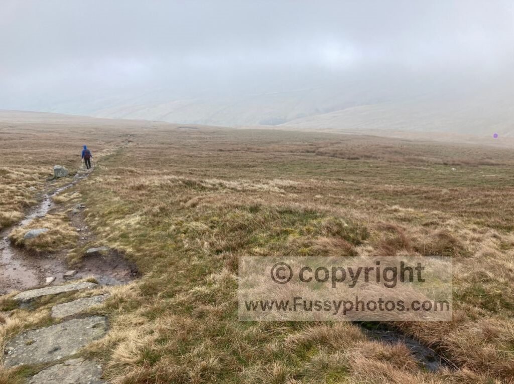 Descent from Great Shunner Fell towards Thwaite, with Swaledale mostly hidden by cloud as the path drops below the mist.