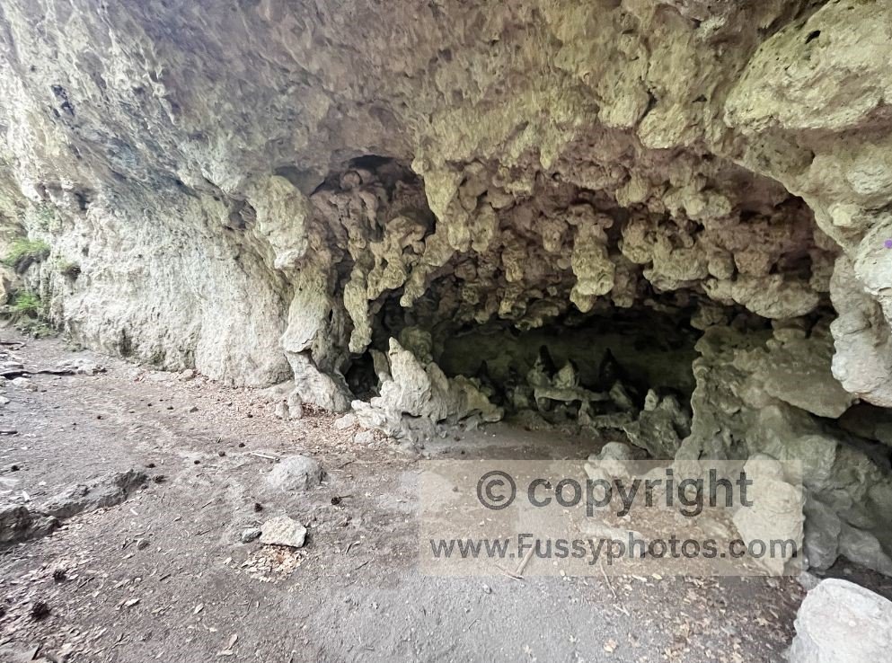 A shaded limestone alcove at The Grotto on the McKittrick Canyon Trail in Guadalupe Mountains National Park, with stone picnic tables beneath the cliffs.