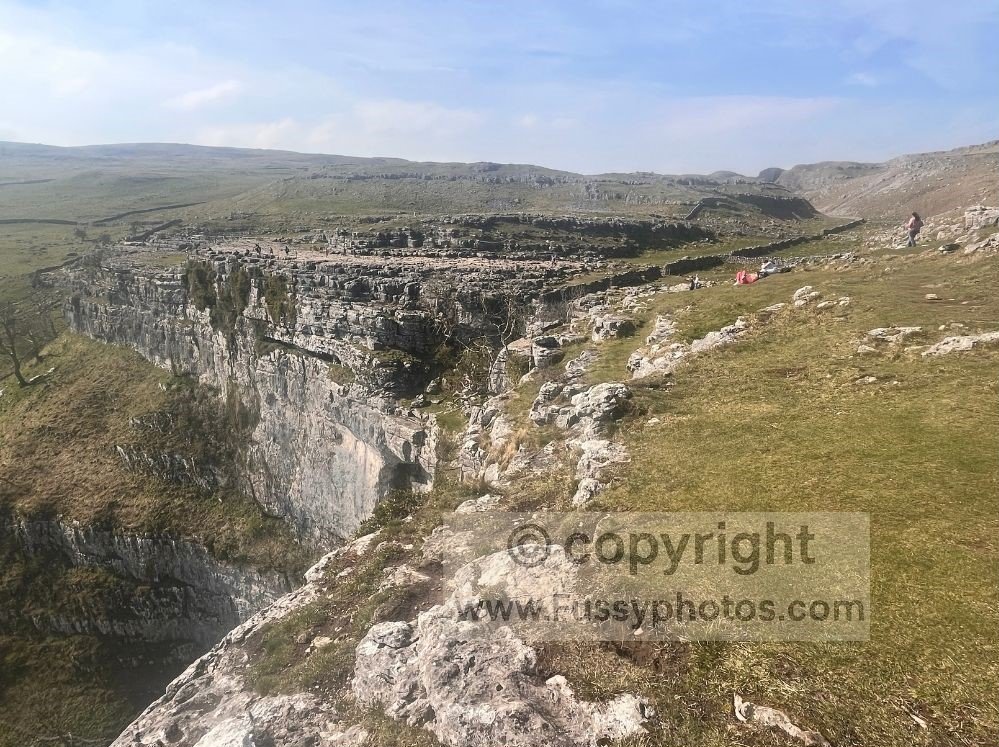 Panoramic view of Malham Cove with the limestone pavement and a clear line up Ing Scar, taken from the western approach on the Dales High Way.