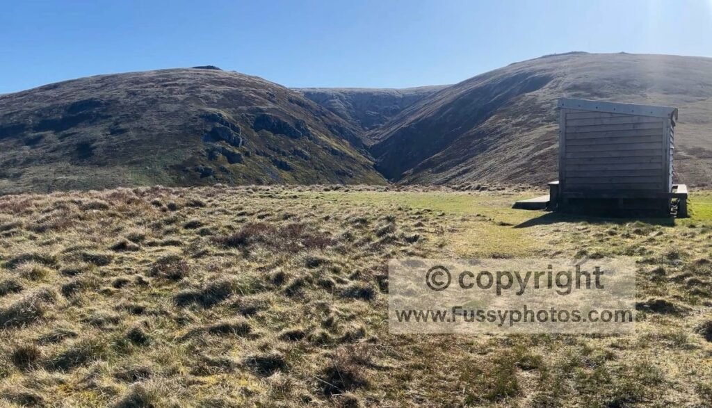 Auchope Mountain Rescue Hut in the foreground with the steep ascent towards The Cheviot and Auchope Cairn behind.