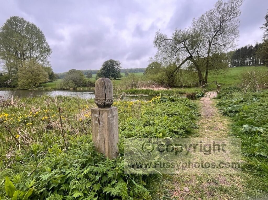 Lake and small bridge inside Londesborough Park on the Yorkshire Wolds Way, showing the more varied scenery walkers reach after the Goodmanham section.