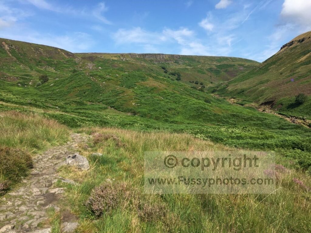 Mid‑ascent view of the climb to Laddow Rocks, with steep moorland and the gritstone edge visible ahead.