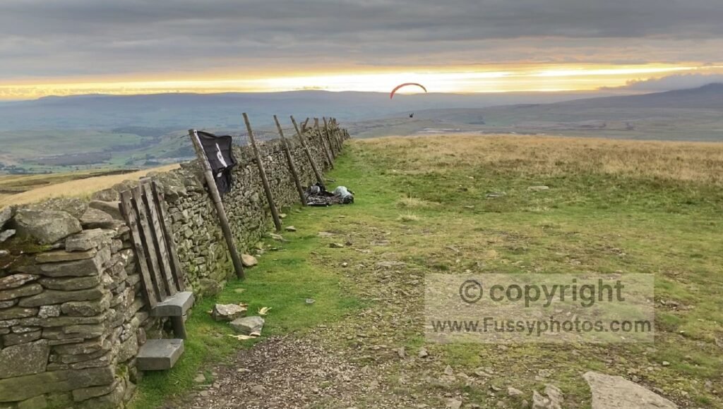 Sunset view of Pen‑y‑ghent with a paraglider crossing the sky.