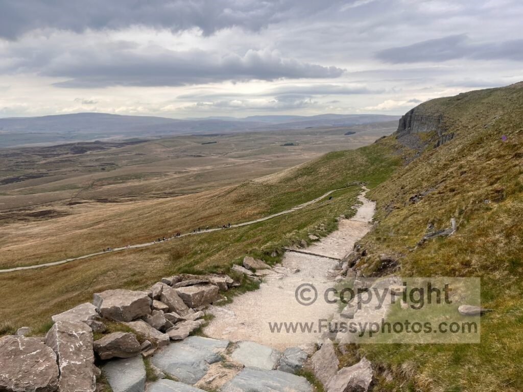 Looking north from the western descent of Pen‑y‑Ghent, with a long view down Ribblesdale and the path cutting across the steep flank.