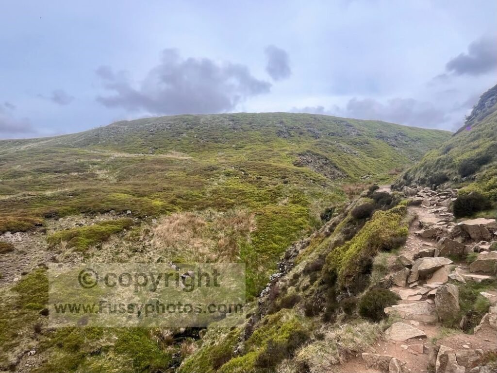 Urchin Clough steep valley section — Photo of the dramatic hillside section in Urchin Clough, where the trail runs across steep ground before meeting the Pennine Way paving stones.