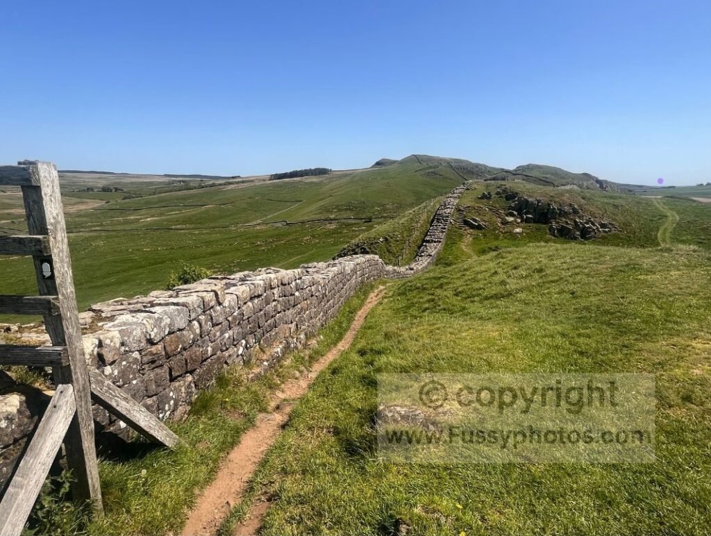 Pennine Way hugging Hadrian’s Wall with lower Military Way visible — Photo showing the Pennine Way closely following Hadrian’s Wall, with the Roman Military Way visible as a lower, easier path to the right.