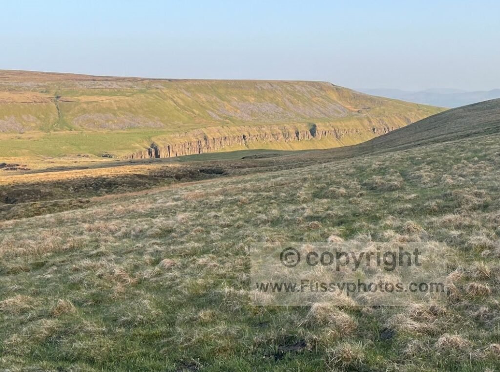 Approach to High Cup Nick alt — Photo showing the first sight of High Cup Nick ahead, a narrow break in the skyline emerging from an otherwise featureless moor.