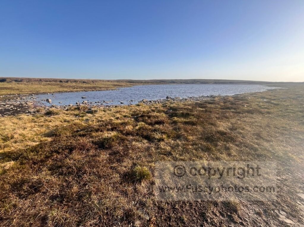 Great Rundale Tarn alt text — Photo of Great Rundale Tarn at the end of the gravel track, marking the transition to open moorland.