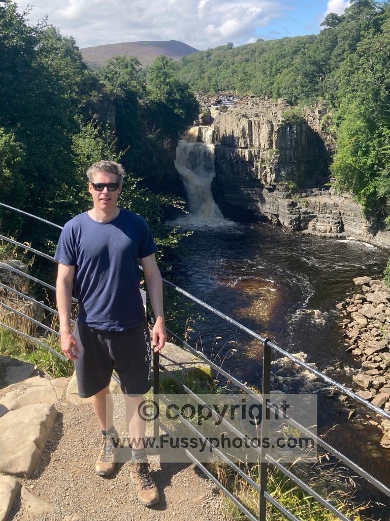 Person standing at the viewpoint with High Force waterfall visible behind.