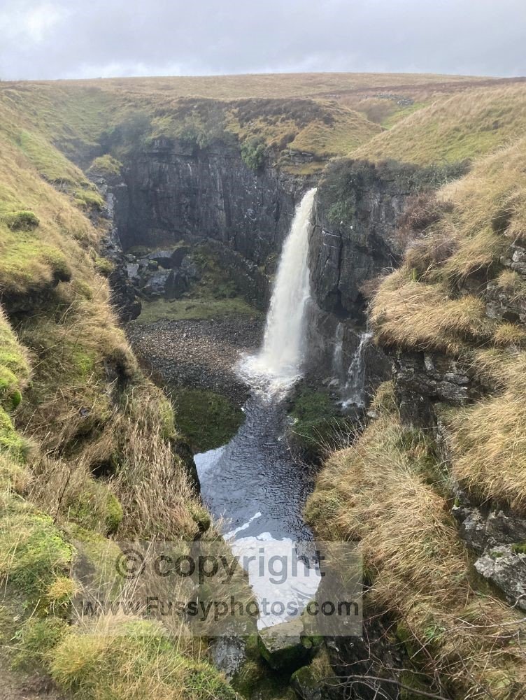 Hull Pot in wet conditions with a waterfall pouring into the collapsed cavern, viewed near the end of the walk into Horton.