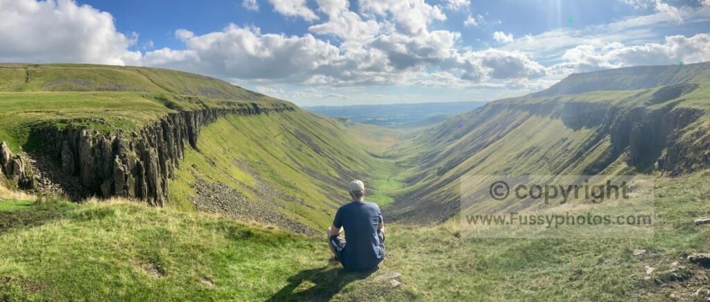 Walker posing in front of High Cup Nick, showing the sweeping glacial valley and central misfit stream.