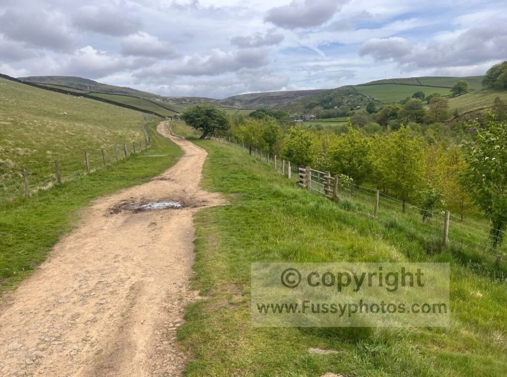 Track east of Old Glossop — Looking east along the track past a farm towards the opening contours of Doctor’s Gate on the approach from Old Glossop.