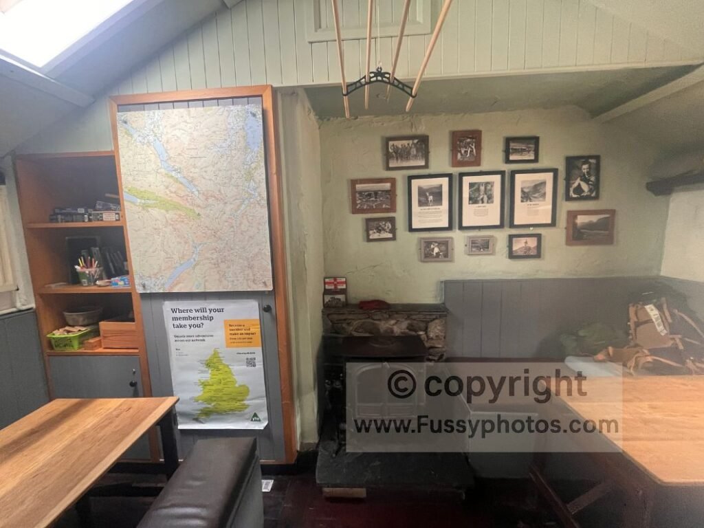 Interior of Black Sail Hut with maps on the walls, indoor benches and the communal reception space used by Coast to Coast walkers.