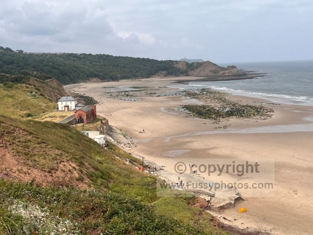 View of Cayton Sands showing the wide beach and The Salty Dog snack stand at the rear, with Lebberston Cliff rising above the bay on the Cleveland Way between Scarborough South Bay and Filey.