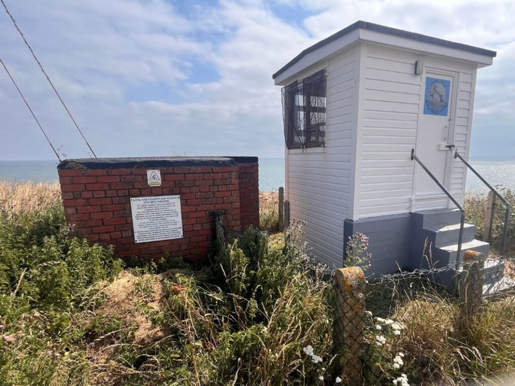 Information board at Long Nab beside the former WWII Mine Lookout and coastguard shelter, reached after the bracken‑lined coastal path curves parallel to Hundale Point on the Cleveland Way.