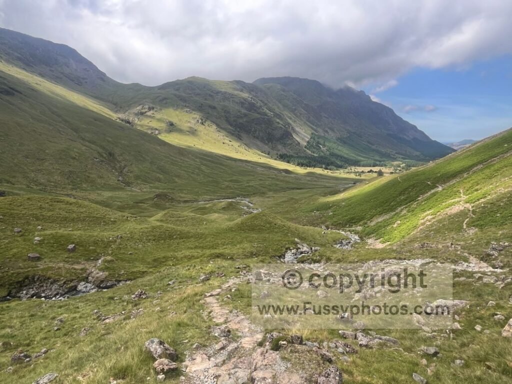 View of the steep Loft Beck descent, with stone steps falling quickly into the glaciated valley and the Ennerdale fell plantations visible in the distance.