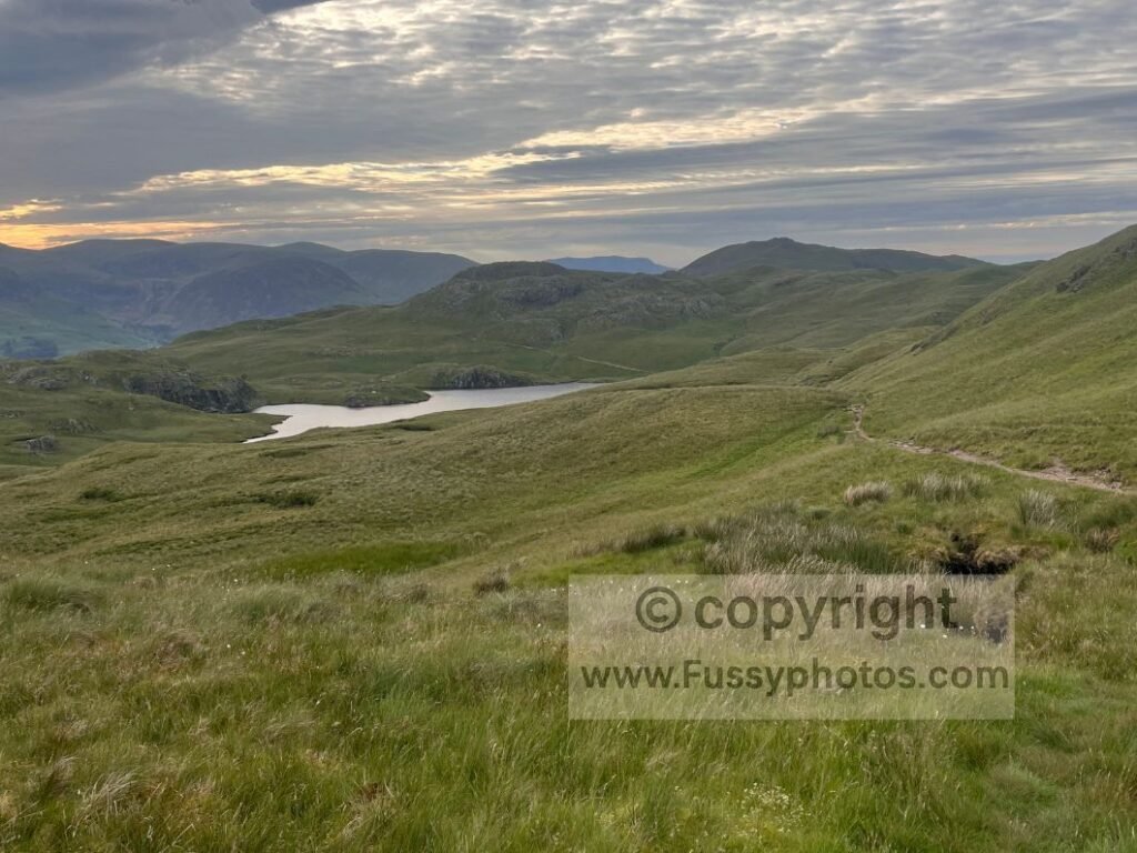 Evening approach to Angle Tarn, taken as the trail skirted the eastern side and tents appeared around the tarn’s edges, revealing its unexpectedly large scale.