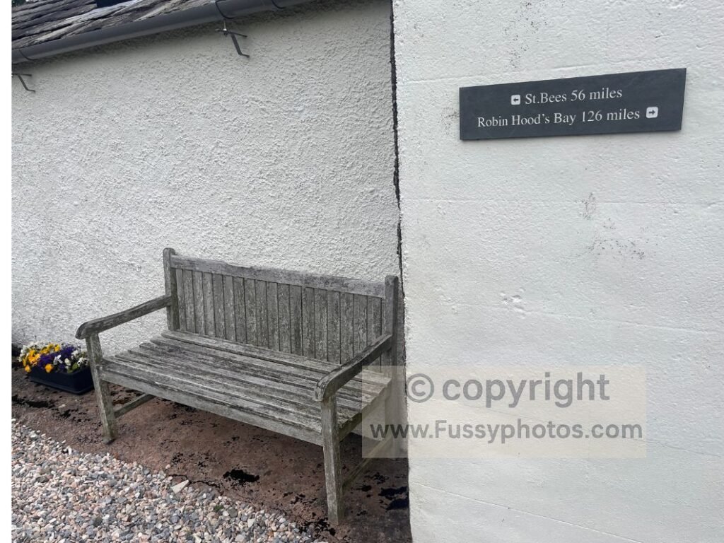Mileage sign showing distances to Robin Hood’s Bay and St Bees above a bench on the Coast to Coast route in North Yorkshire and Cumbria.