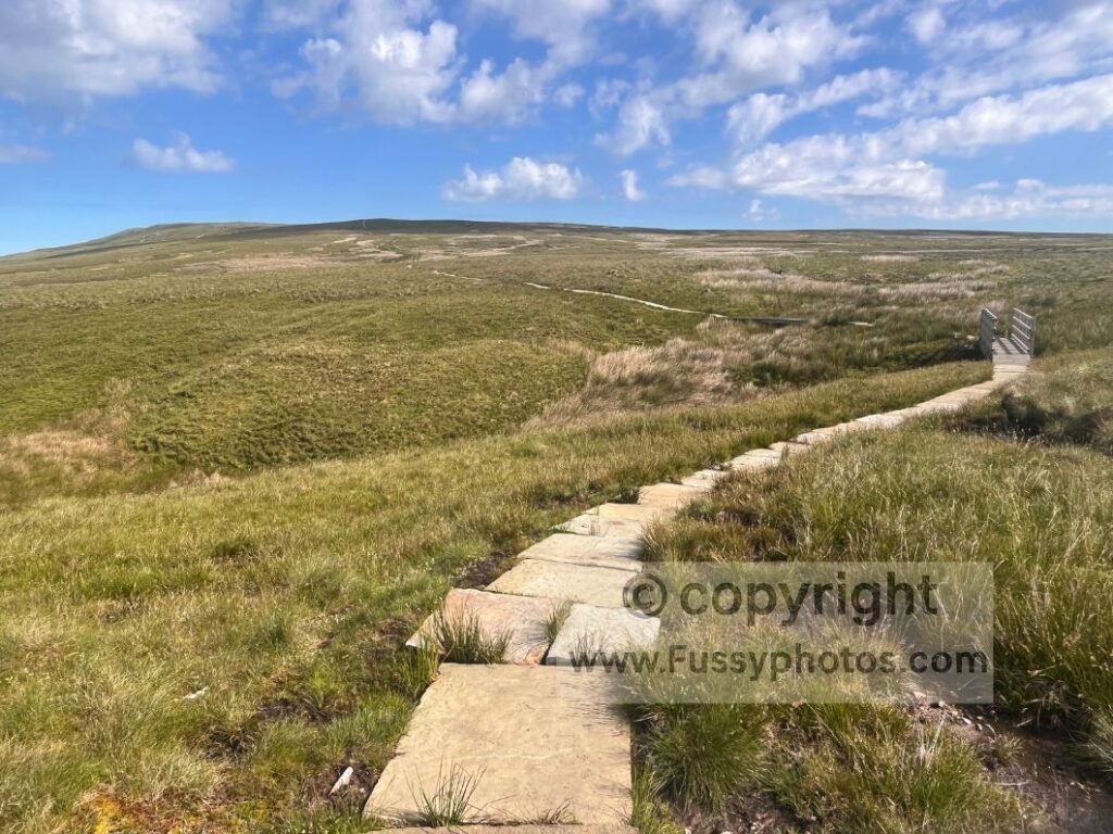Long flagstone path ascending over Birkdale Common towards Nine Standards Rigg, showing the paved route installed to aid walkers across this exposed, challenging section.