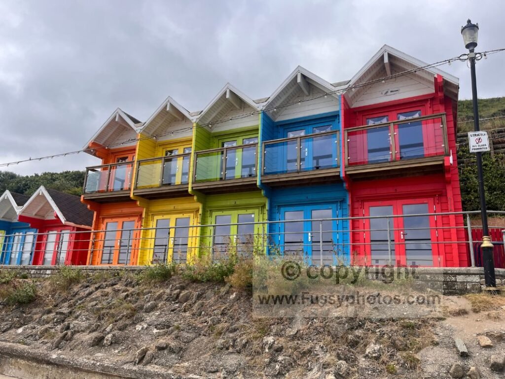 Row of colourful chalets at Scarborough North Bay, seen from the Cleveland Way as the route stays close to the beach past pubs, sea walls and the Sea Life Centre.