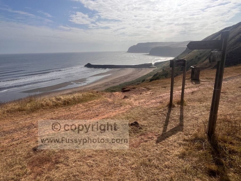 View east over Cattersby Sands from Cattersby Cliff, showing a wide empty beach framed by high coastal cliffs on the Cleveland Way.