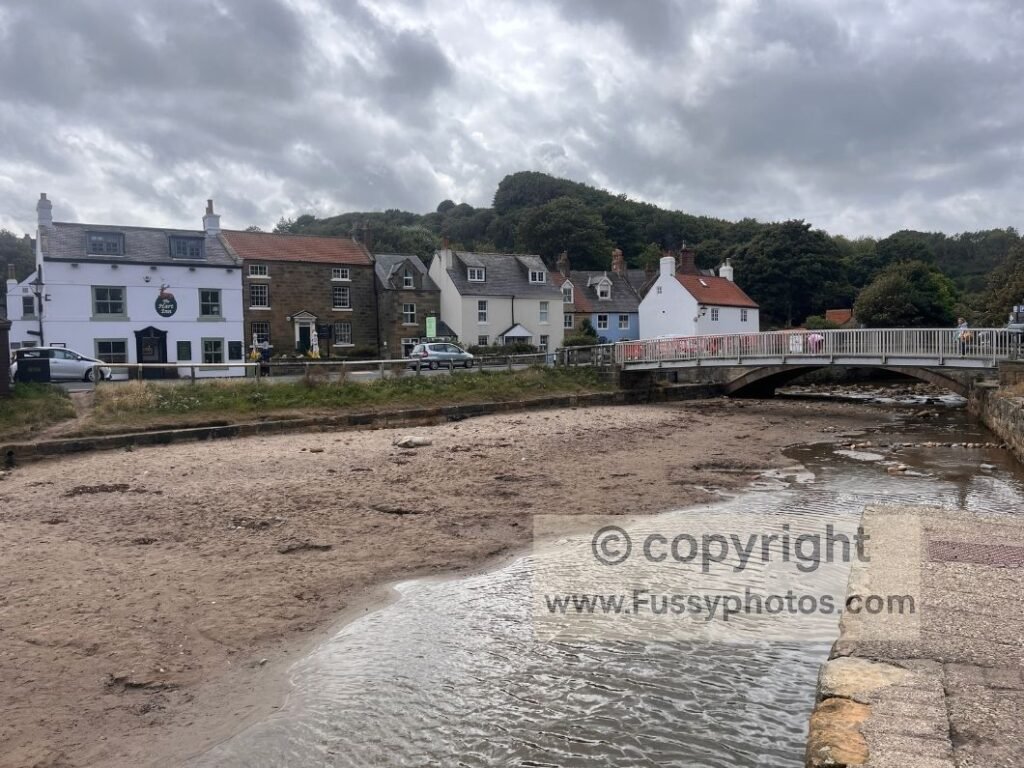 Sandsend beach photographed from a bench above East Row Beck, with The Hart Inn visible in the background.