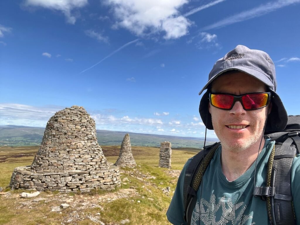 Walker carrying a full backpack on Nine Standards Rigg above Kirkby Stephen on the Coast to Coast, highlighting how pack weight affects pace and fatigue.