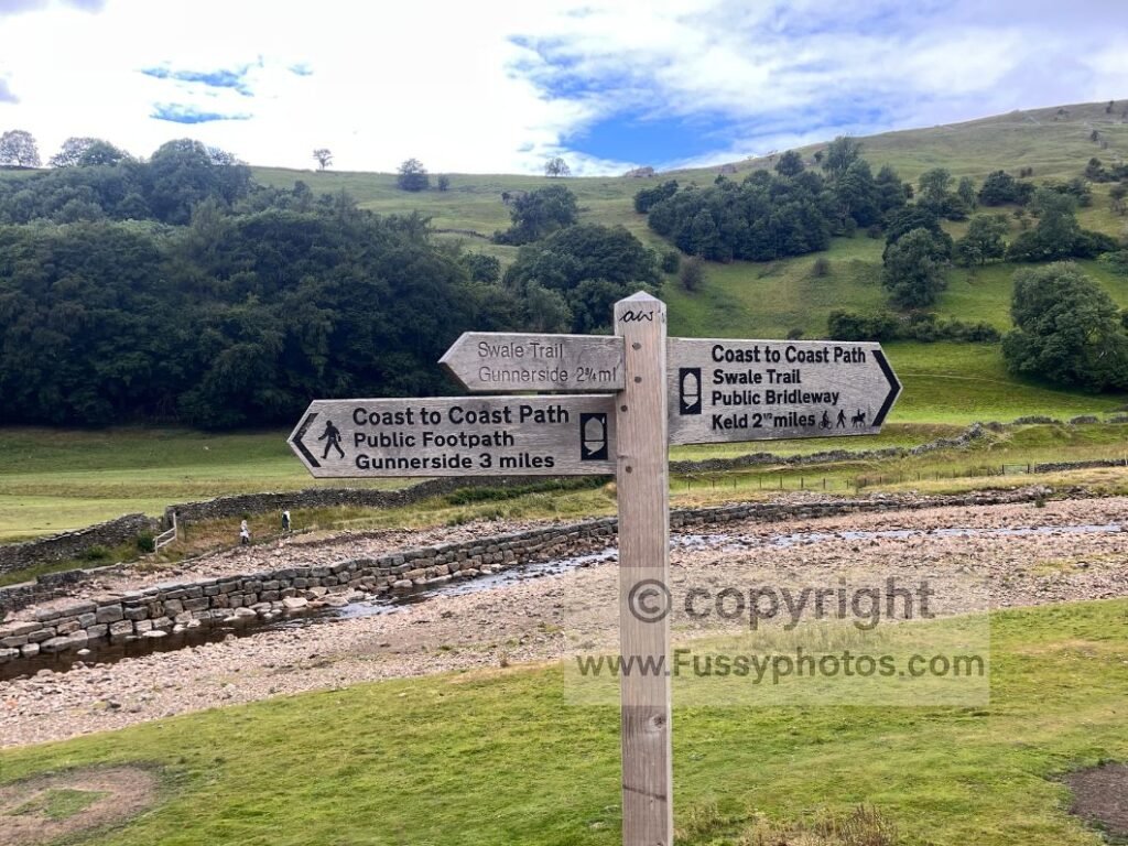 Trail finger post along the River Swale low‑level alternative, marking an easy navigation point for choosing flexible Coast to Coast splits in the context of Choosing the Right Coast to Coast Split for You.