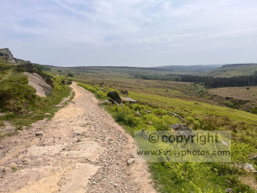 South‑facing view on the lower Burbage Rocks trail, showing wide paths, scattered boulders and the higher Upper Burbage route above.