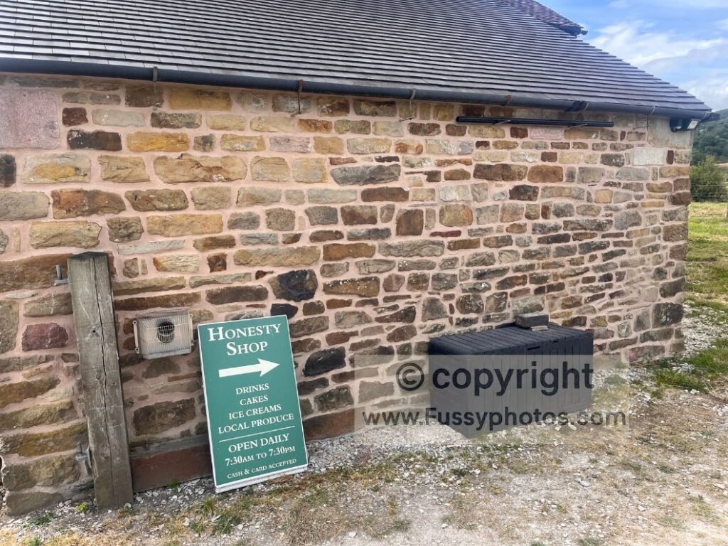 Honesty box sign at the Old School House near Chrome Hill, with benches and ridge views nearby.